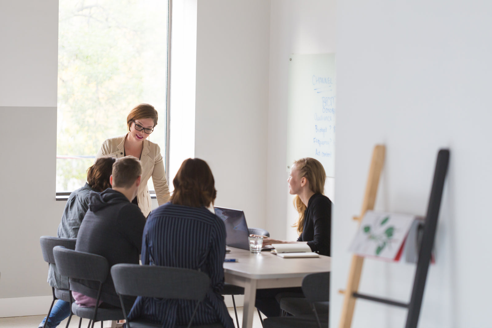 A small team collaborating around a laptop in a meeting